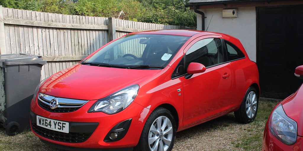 A small red hatchback parked at the kerb
