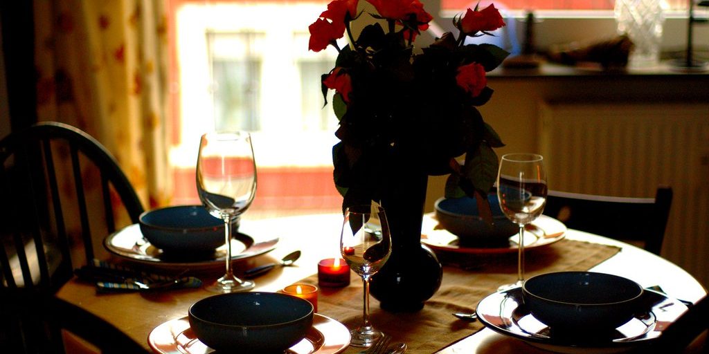A dinner table laid with wine glasses and flowers, waiting for guests