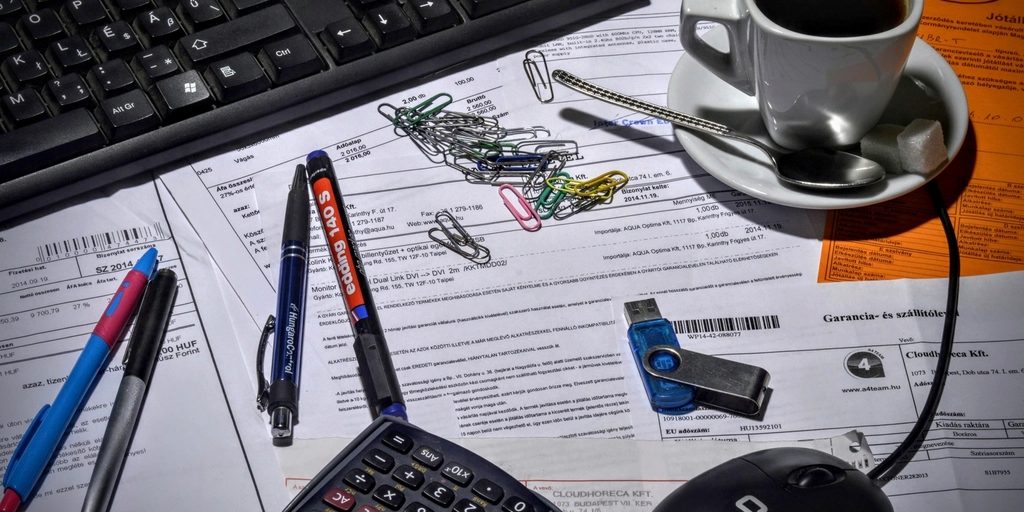 A desk with paperwork, a pen and a cup of coffee