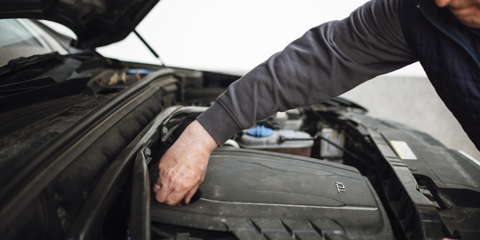 A mechanic working under the bonnet of a car