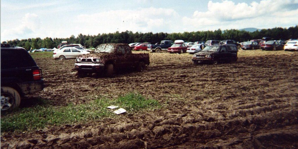 Cars parked across a muddy festival field