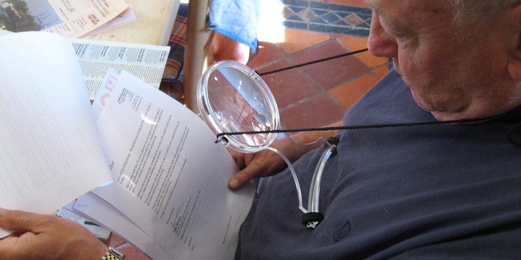 A person examining paperwork with a magnifying glass